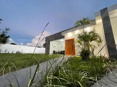 a white house with a wooden door and grass at Villa Ferrer I in Jarabacoa