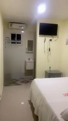 a bedroom with a white bed and a flat screen tv at Hotel 3 Hnos in Comendador