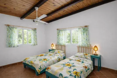 two beds in a room with two windows at Casa los Mangos Private pool 150 m from the beach in Las Galeras