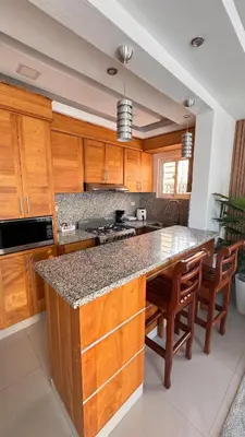 a kitchen with wooden cabinets and a large island with chairs at Coastal Apt, Near Malecón, 6 Guests 3 beds in La Romana