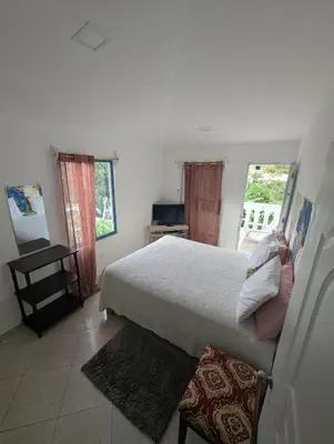 a bedroom with a large white bed and two windows at small apartment in a downtown area in Cruce de Veragua