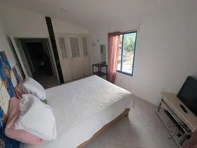 a bedroom with a white bed and a television at small apartment in a downtown area in Cruce de Veragua