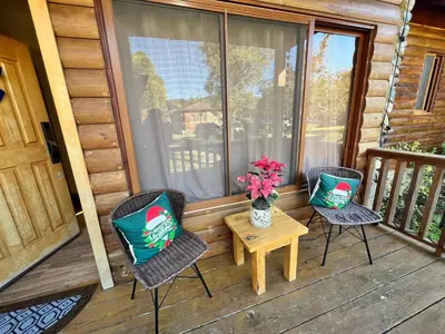 two chairs and a table on a porch with a vase of flowers at Estaciones de Jarabacoa - Mountain Lodge in Jarabacoa