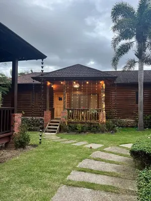 a wooden house with a porch and a palm tree at Estaciones de Jarabacoa - Mountain Lodge in Jarabacoa
