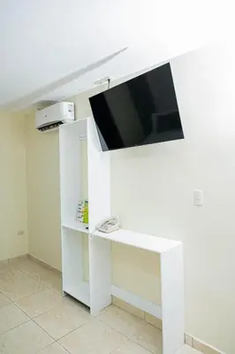 a white stand with a flat screen tv on a wall at Hotel Monterio in Azua