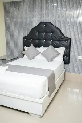 a bedroom with a large bed with a black headboard at Hotel Monterio in Azua