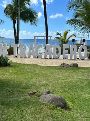 a large sign on a beach with palm trees and the ocean at 1BR Tracadero Lodge, beach access & full amenities in La Laguna