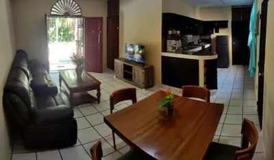 a living room with a wooden table and a kitchen at Tortuga Cabarete Resindencial in Sosua