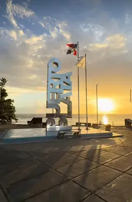 a large metal sculpture in front of the ocean with flags at EG suits rentals in San Felipe de Puerto Plata