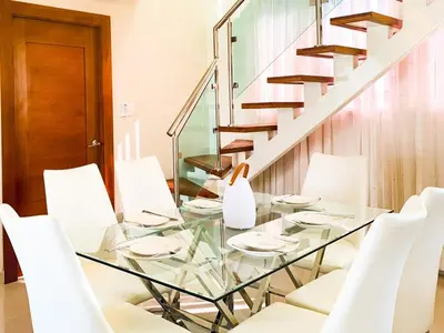 a glass table with white chairs and a staircase at Serene Penthouse near Homs Hospital in El Ejido
