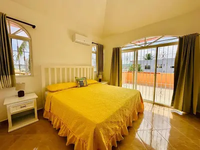 a bedroom with a yellow bed and a large window at Villa Tropical Cabarete in Sosua