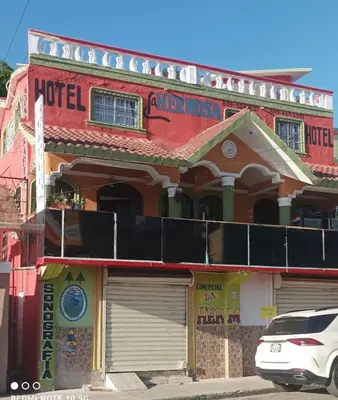 a white car parked in front of a building at Hotel Pensión la Hermosa Barahona in Santa Cruz de Barahona