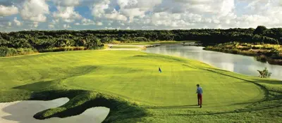 a man standing on a golf green next to a river at Vista Velero – 1BR Coastal Escape @ Cana Rock Star in Punta Cana