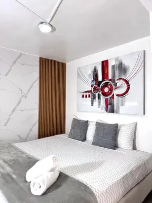 a bedroom with a bed with a painting on the wall at Estudio Elegante 10 minutos del Monumento & Agora mall in Santiago de los Caballeros