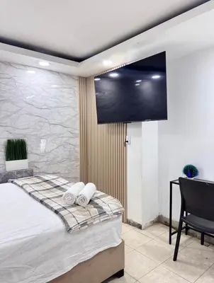 a bedroom with a flat screen tv on the wall at Estudio Elegante 10 minutos del Monumento & Agora mall in Santiago de los Caballeros