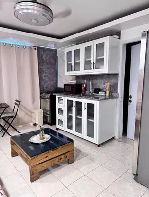 a kitchen with white cabinets and a coffee table at Estudio Elegante 10 minutos del Monumento & Agora mall in Santiago de los Caballeros