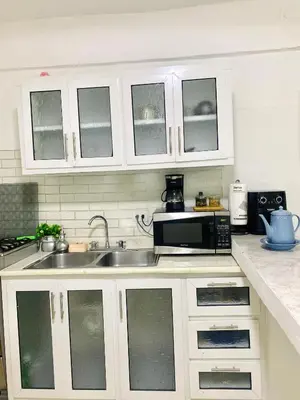 a kitchen with white cabinets and a sink and a microwave at Apartment with Everything AC Wifi and Solar panel in Bonao