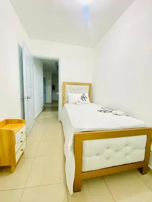 a bedroom with a large bed and a wooden dresser at Centrally located Comfortable Apartment in Bonao