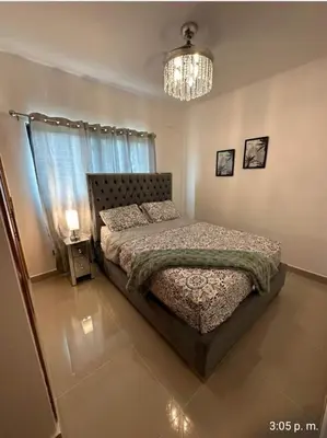 a bedroom with a bed and a chandelier at Tranquilo y acogedor in Santiago de los Caballeros