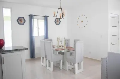 a white dining room with a table and chairs at Byk in Nagua