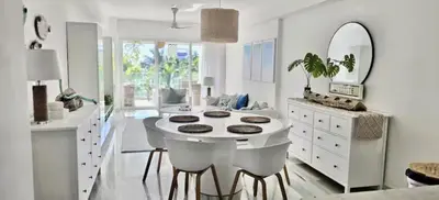 a white kitchen with a round table and a mirror at Seawinds Beachfront -Top Floor Less Mosquitos -Full Security in Cabarete