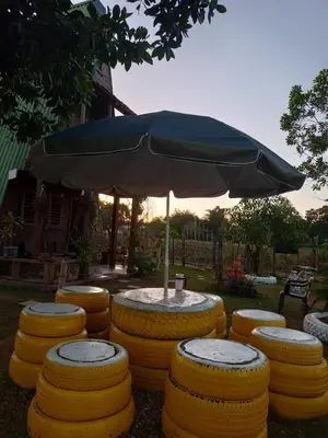 a table with an umbrella and some yellow stools at Mi casita de Campo en Bayaguana in Bayaguana