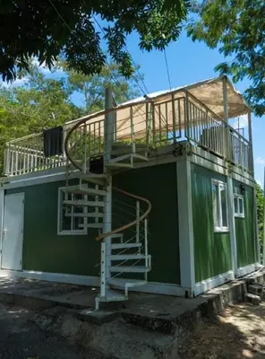 a small green house with a deck and stairs at Villa María 2 in Bonao