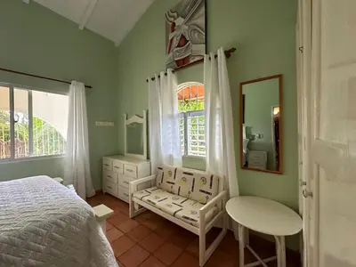 a bedroom with a bed and a chair and a mirror at Casa pintada - 4 people, 4 minutes from the beach in Las Galeras