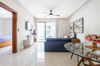 a living room with a blue couch and a glass table at Quiet 1-Bedroom Apartment with Pool View in Gated Bávaro Residence in Punta Cana