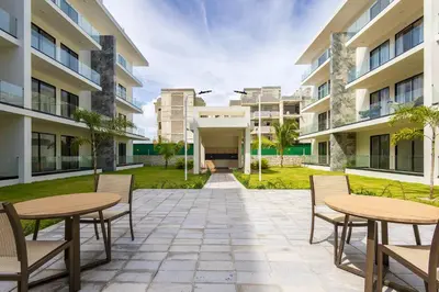a courtyard with tables and chairs in front of buildings at Quiet 1-Bedroom Apartment with Pool View in Gated Bávaro Residence in Punta Cana