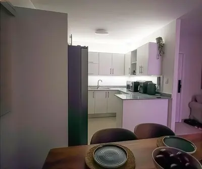 a kitchen with pink and white cabinets and a table at San Isidro Urban Suite in Juan López