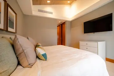 a bedroom with a bed with pillows and a flat screen tv at Luxury Guesthouse Villa with Golf Cart - Casa de Campo in La Romana