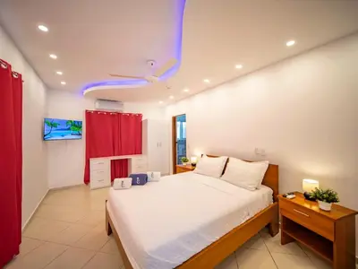 a bedroom with a large bed and a red curtain at Plaza Achim 2BR APT heart of nightlife area in Sosúa