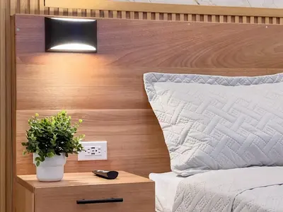 a bed with a wooden headboard and a plant on a night stand at Plaza Achim 7 Luxury Apt 250m from Sosua Beach in Sosúa