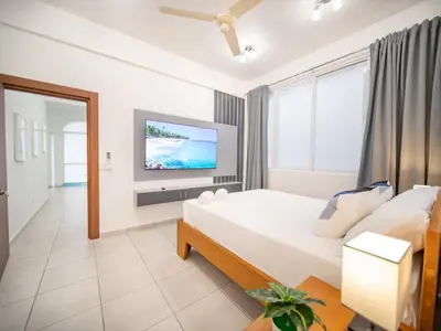 a bedroom with a bed and a flat screen tv at Plaza Achim 6B, Modern APT 250m from Sosua beach! in Sosúa