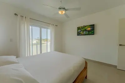 a white bedroom with a bed and a window at Prime Apartment with Fast Internet & Washer in SOV in Sosúa