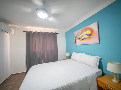 a bedroom with a white bed and a blue wall at Garden Condos 10 2BR Apt in Sosua Strip in Sosúa