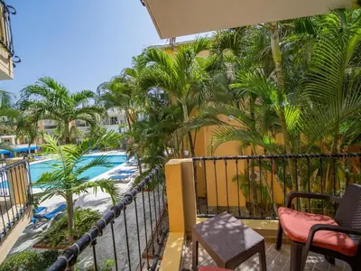 a balcony with a view of a pool and palm trees at Garden Condos 10 2BR Apt in Sosua Strip in Sosúa