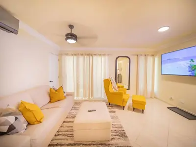 a living room with a white couch and yellow chairs at Garden Condos 21 Modern 1BR APT in Sosua Strip in Sosúa