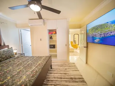 a bedroom with a bed and a flat screen tv at Garden Condos 21 Modern 1BR APT in Sosua Strip in Sosúa
