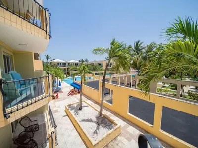 an apartment balcony with a swimming pool and palm trees at Charming 1BR Apt with Pool Walk to Sosua Beach in Sosúa