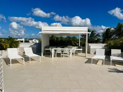 a patio with white chairs and a table and a pavilion at Luxury Penthouse with roof top & infinitive pool ocean view in Tracadero Beach Club in Bayahibe