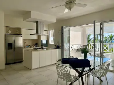 a kitchen with a glass table with chairs and a refrigerator at Luxury Penthouse with roof top & infinitive pool ocean view in Tracadero Beach Club in Bayahibe