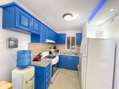 a kitchen with blue cabinets and a white refrigerator at Garden Condos 43 Modern Condo in Sosua center in Sosúa