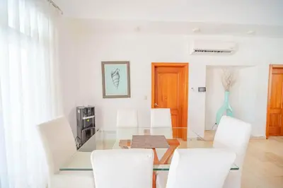 a dining room with a glass table and white chairs at Luxury 2BR Villa next to Santa Fe in Sosúa