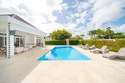 a swimming pool with lounge chairs and a house at Luxury 2BR Villa next to Santa Fe in Sosúa