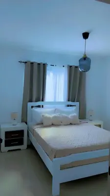 a bedroom with a white bed with a blue light at Appartement lumineux, piscine & plage proche in Punta Cana
