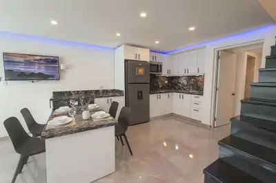 a kitchen with white cabinets and a table and chairs at Stylish Sosua 2 BR apartment near everything in Sosúa