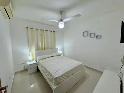 a white bedroom with a bed and a ceiling fan at Modern apartment in Gurabo Santiago in Santiago de los Caballeros