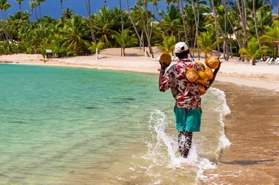 a man walking in the water with coconuts on his back at Luxury Villa in Punta Cana in Punta Cana